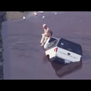 Man sits on car as it is miles swallowed by sinkhole
