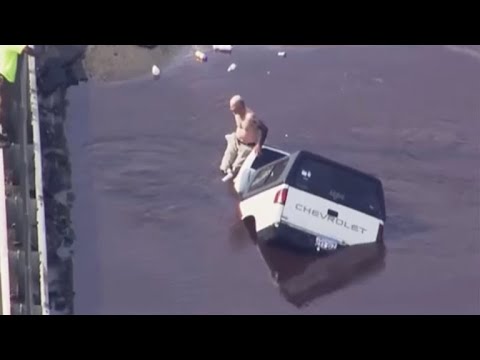 Man sits on car as it is miles swallowed by sinkhole